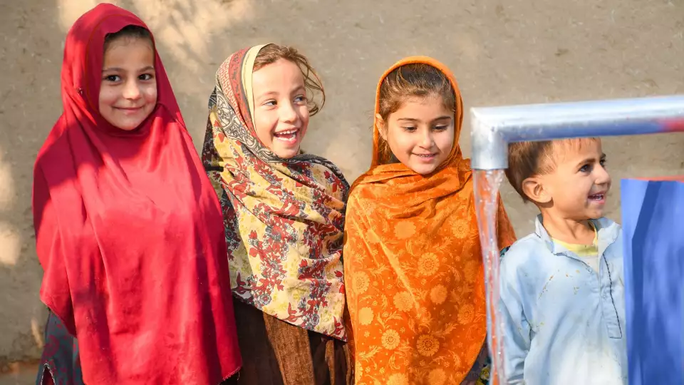 Siblings patiently wait in line for their turn to enjoy refreshing, clean water.