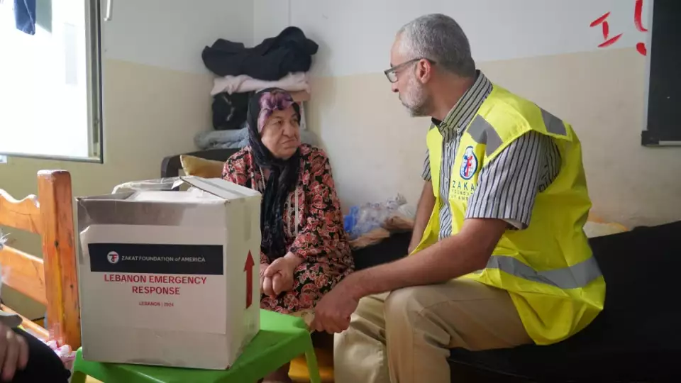 An elderly woman in Lebanon receives an emergency kit as she seeks safety at a local shelter.