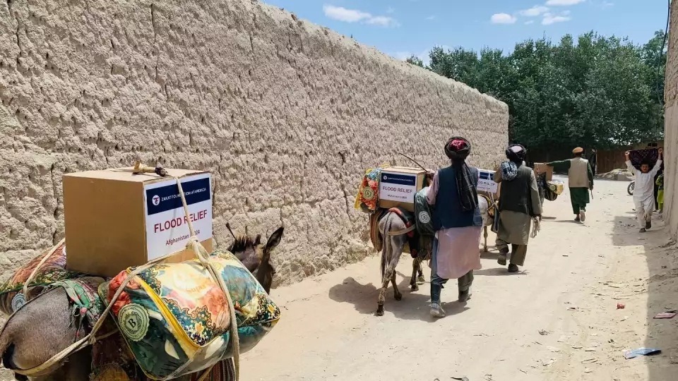 Families in Afghanistan use mules to carry home flood relief supplies.