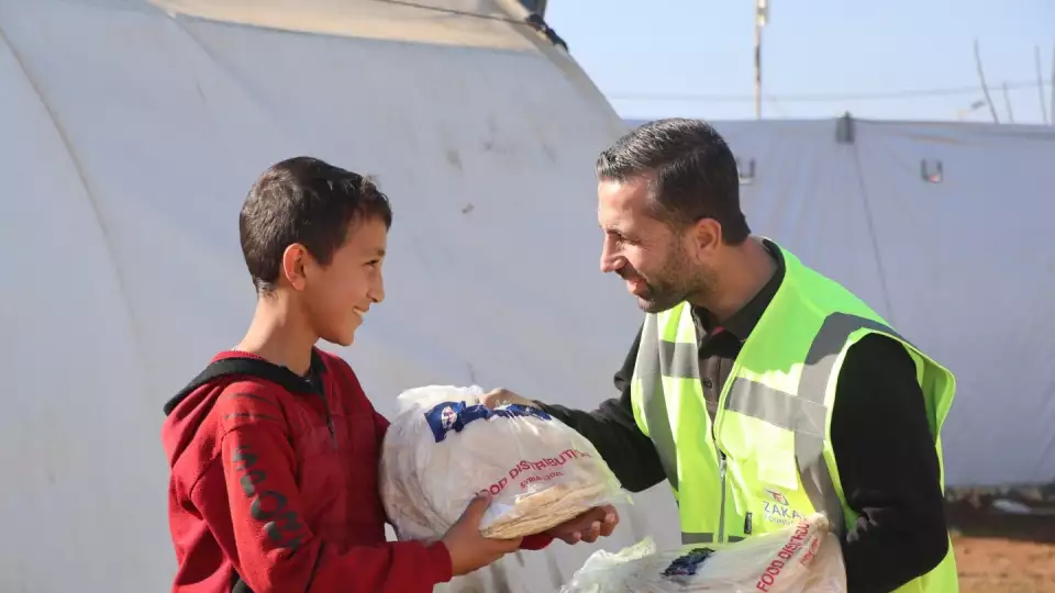 A displaced boy in Syria receives fresh bread from our field team as emergency relief efforts continue.