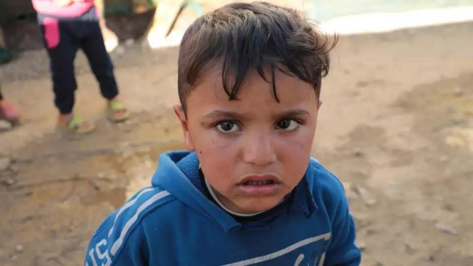 A young boy wanders through a tent village in Lebanon