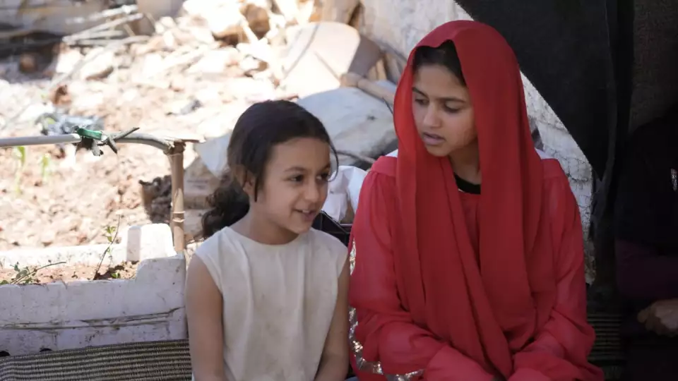 Two young girls converse amongst their tent village home