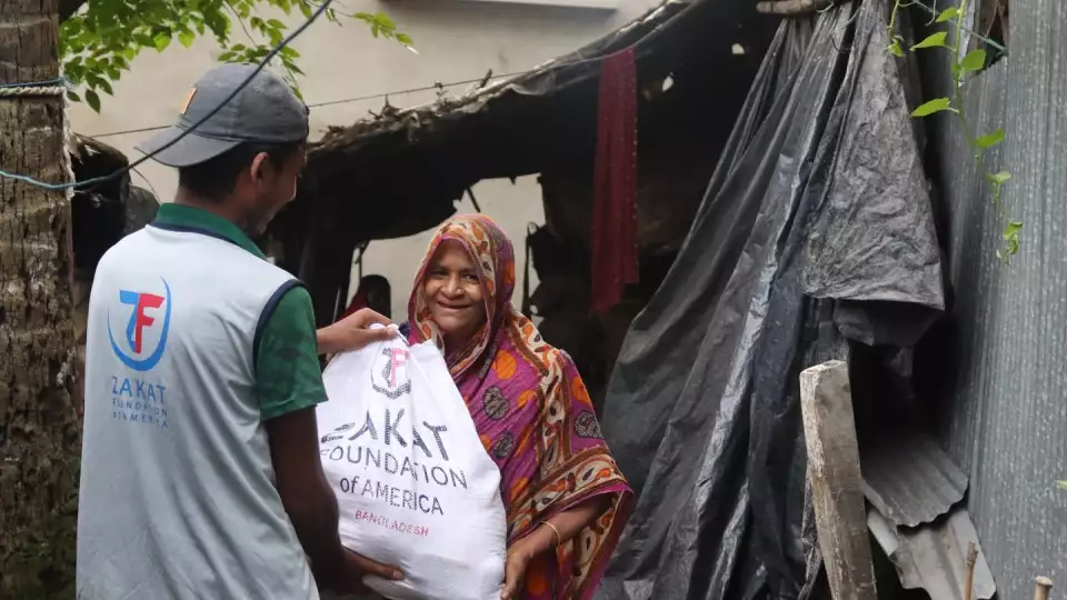A Bangladeshi women smile from relief as she receives flood relief essentials from our field teams.