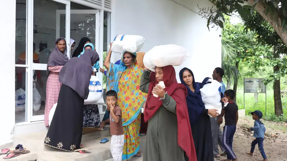 Families in Sri Lanka carry flood relief items home.