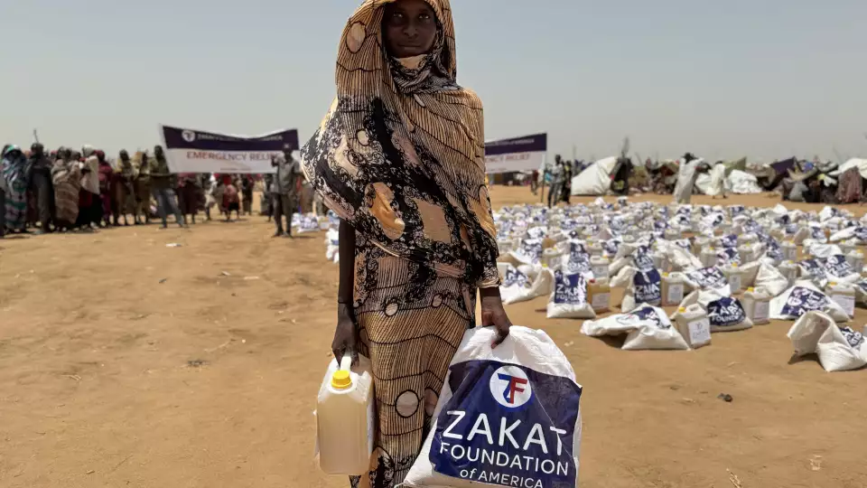 A young women from Sudan takes home food items to help feed her displaced family